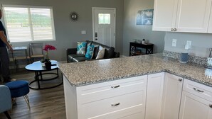 A modern kitchen with white cabinets, granite countertops, and a dining area with a table and chairs. - 🌻Sunflower Cottage🌻Breathtaking Mountain Views & Fresh Air Retreat! (Flagstaff)