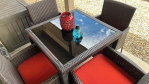 A square outdoor table with a glass top, surrounded by wicker chairs with red cushions. - 🌻Sunflower Cottage🌻Breathtaking Mountain Views & Fresh Air Retreat! (Flagstaff)
