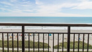A beach view from a balcony with a railing, sandy beach, and ocean. - Tranquility: 6th Floor 1 Bedroom Oceanfront Suite (Myrtle Beach)