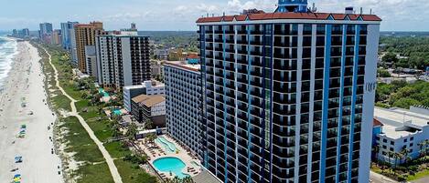 A high-rise hotel with a rooftop pool, beach access, and a view of the ocean.