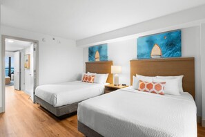 Two single beds with wooden headboards and white bedding, accompanied by nightstands and lamps, and artwork above.