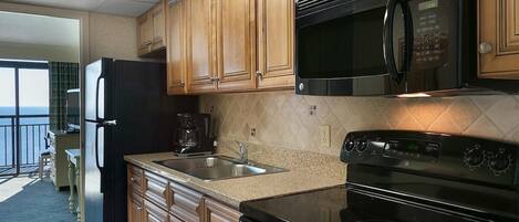 A kitchen with wooden cabinets, a stainless steel refrigerator, a microwave, and an oven.
