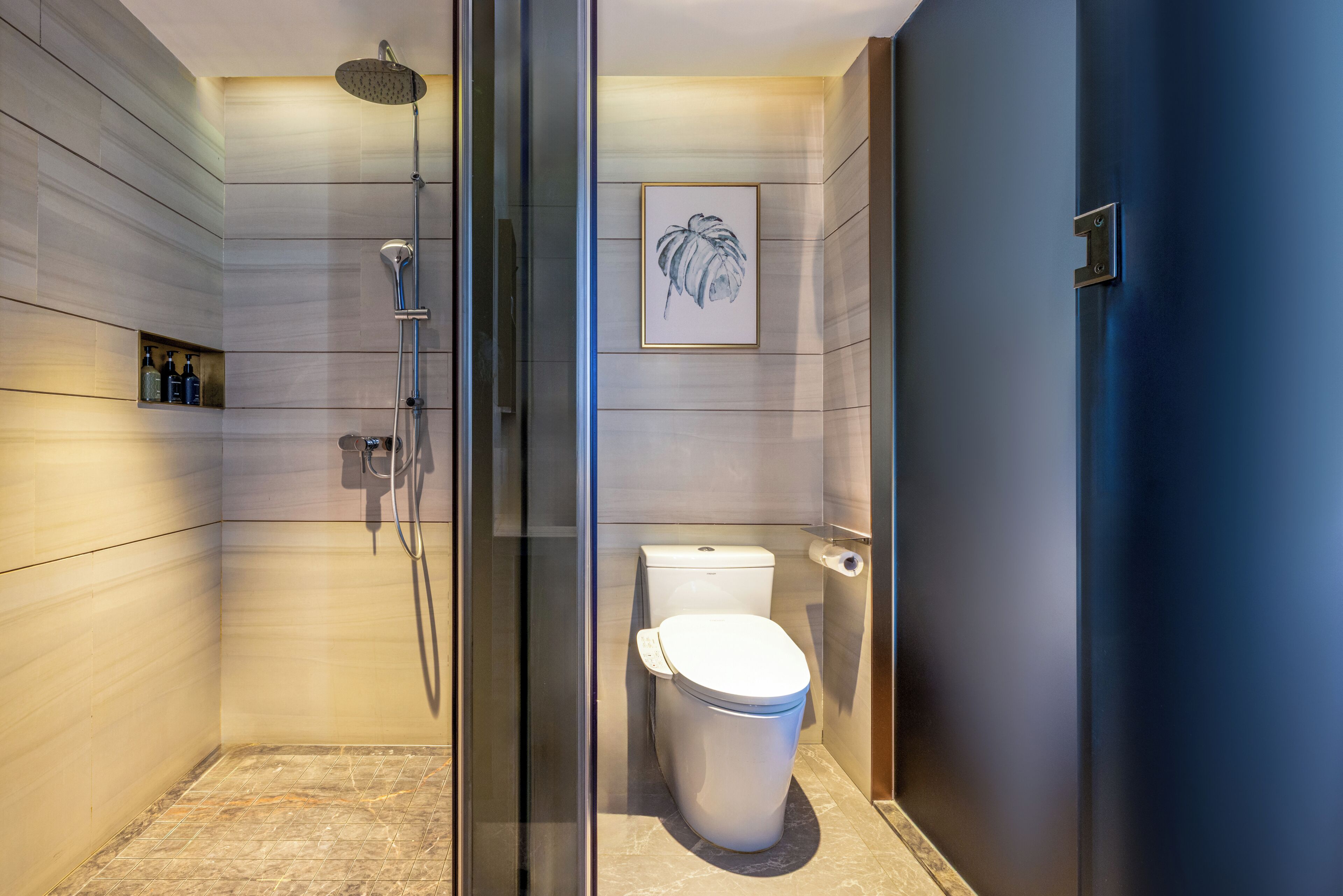 Une salle de bain moderne avec une douche à parois de verre, des toilettes et une œuvre d’art encadrée accrochée au mur.