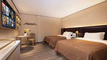 A hotel room with two beds, a small table with a vase of flowers, a television mounted on the wall, and a coat rack.