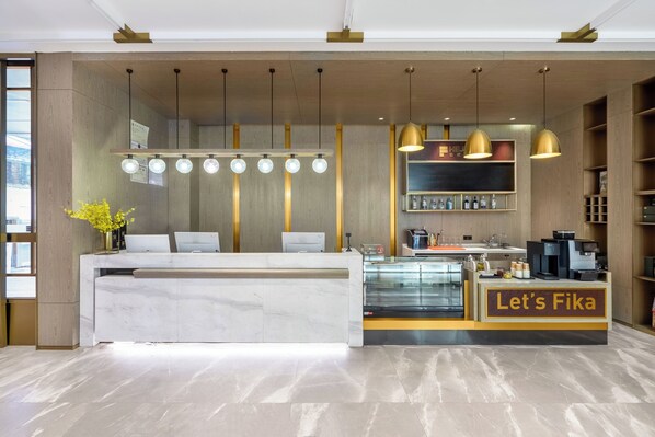 A modern reception area with a marble counter, a glass display case, and a coffee machine. - Housekeeper Hotel Beijing Road Branch (Guangzhou)