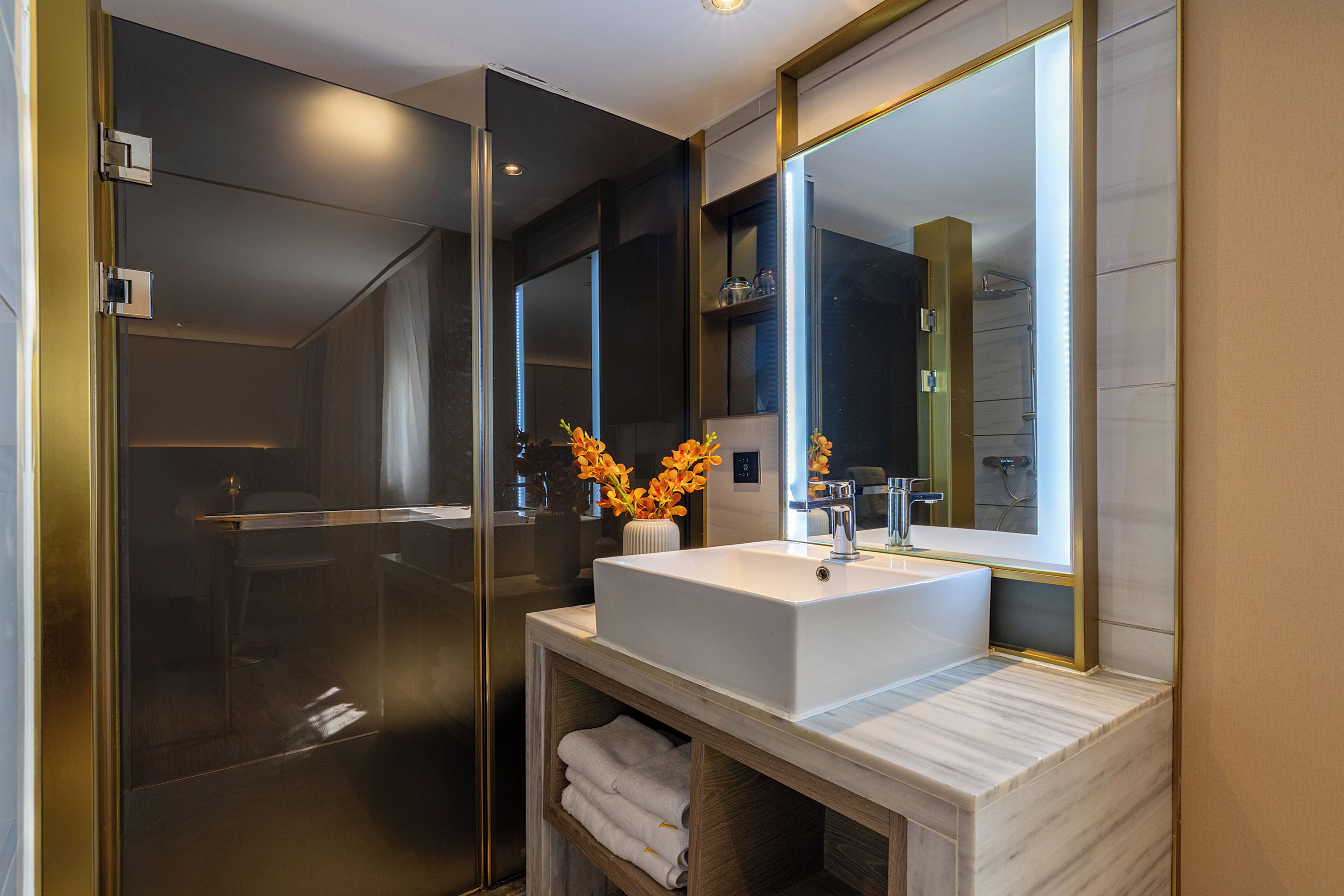 A modern bathroom with a glass-enclosed shower, a white sink, and a large mirror.