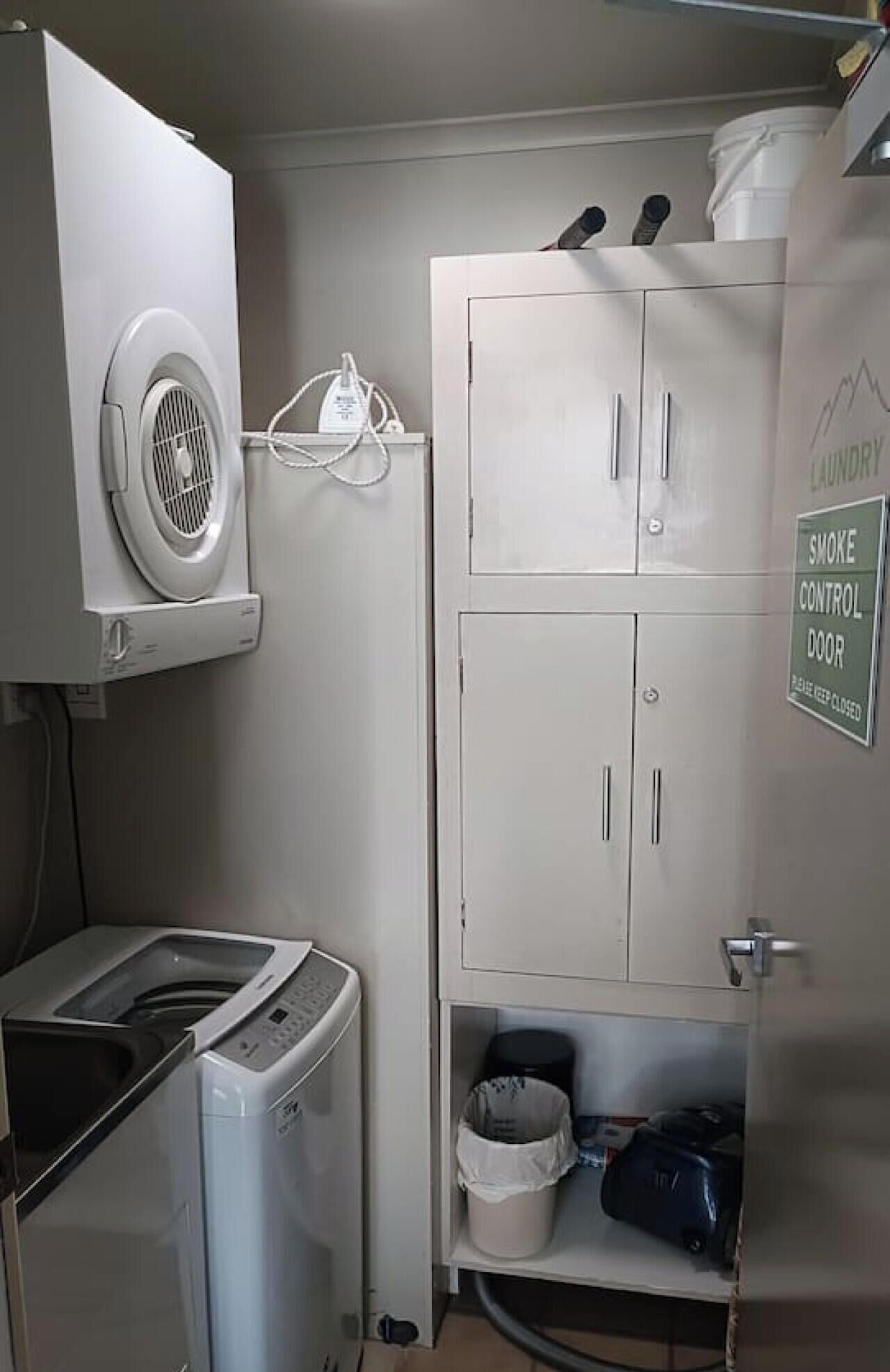 A laundry area with a washing machine, a dryer, and a cabinet with a smoke control door sign.