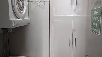 A laundry area with a washing machine, a dryer, and a cabinet with a smoke control door sign.