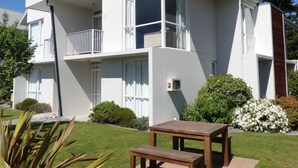 A modern two-story residential building with a balcony, a small garden, and a wooden table. - Opuke Crash Pad Methven - with mountain views. (Methven)