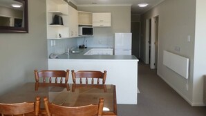 A compact kitchen with a dining table and chairs, a microwave, a refrigerator, and a built-in oven. - Opuke Crash Pad Methven - with mountain views. (Methven)