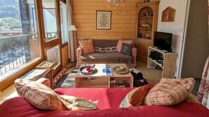 Ein gemütliches Wohnzimmer mit Holzeinrichtung, einer Couch, einem Couchtisch und einem Fernseher.