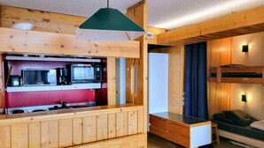 Habitación pequeña y acogedora con paneles de madera, un rincón americano y una cama litera.