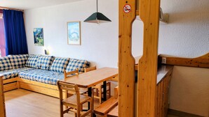 Una habitación acogedora con un sofá de madera, una mesa de comedor con bancos y una lámpara colgante.