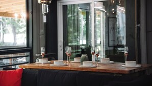Une table à manger dressée avec des assiettes, des verres et un chandelier, avec une fenêtre et une lampe en arrière-plan.