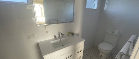 Baño con lavamanos, espejo y retrete blancos.