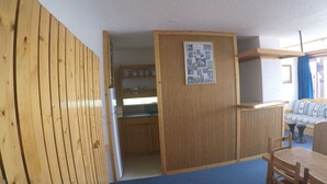Une cuisine de taille réduite, dotée de meubles en bois et d’un réfrigérateur encastré.