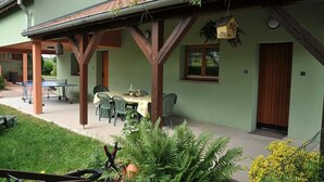 A two-story building with a covered patio area featuring a table and chairs. - Bright and quiet cottage with terrace, barbecue, and parking 5 km from Colmar (Houssen)