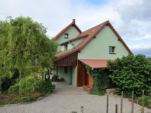 Ein zweistöckiges Haus mit grüner Fassade und rotem Ziegeldach.
