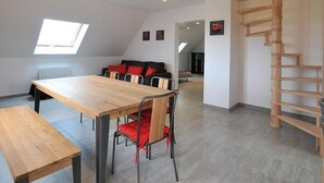 A modern loft apartment with a dining area, a sofa set, a wooden staircase, and a skylight. - Bright and quiet cottage with terrace, barbecue, and parking 5 km from Colmar (Houssen)