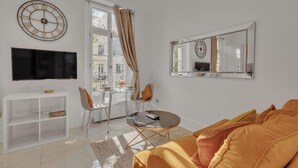 Ein modernes Wohnzimmer mit Sofa, Fernseher und Essbereich mit Stühlen und Tisch.