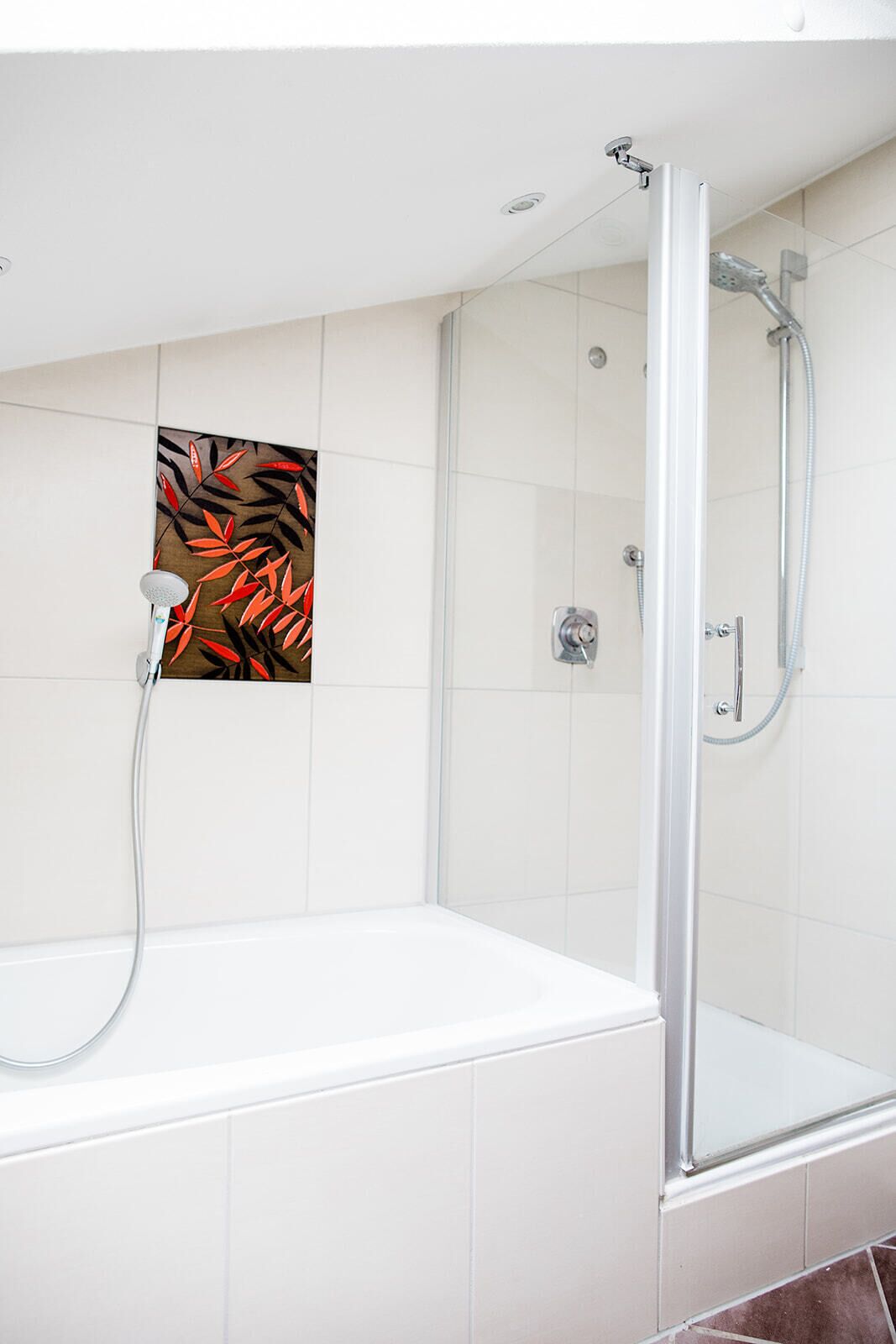 Un baño moderno con ducha envuelta en vidrio, una bañera blanca y un panel decorativo en la pared.