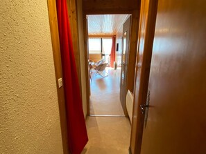 A narrow hallway leading to a room with a chair and a window. - Spacious central studio near gondola, sunny balcony (Châtel)