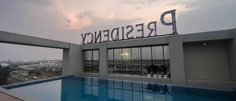 A rooftop pool with a view of the cityscape and a sign that reads "RESIDENCE".
