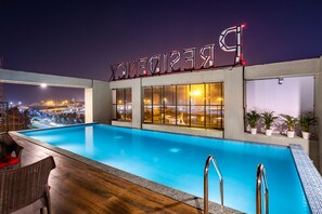 A rooftop pool area with a view of the city at night, a sign reading "RECREATION," and potted plants along the pool's edge. - Presidency Airport Hotel (Aluva)