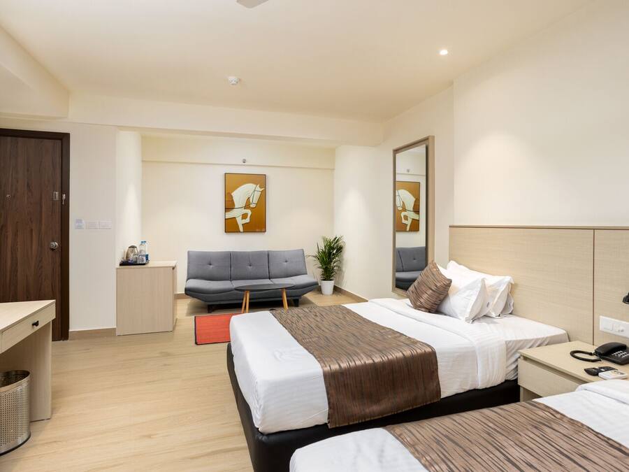 A hotel room with a bed, bedside table, lamp, and a sofa.