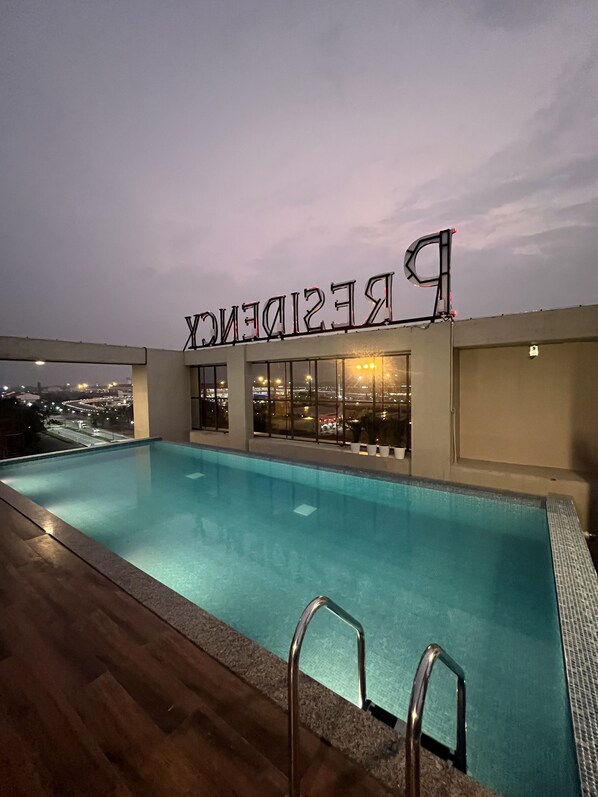 A rooftop pool with a clear view of the cityscape. - Presidency Airport Hotel (Aluva)