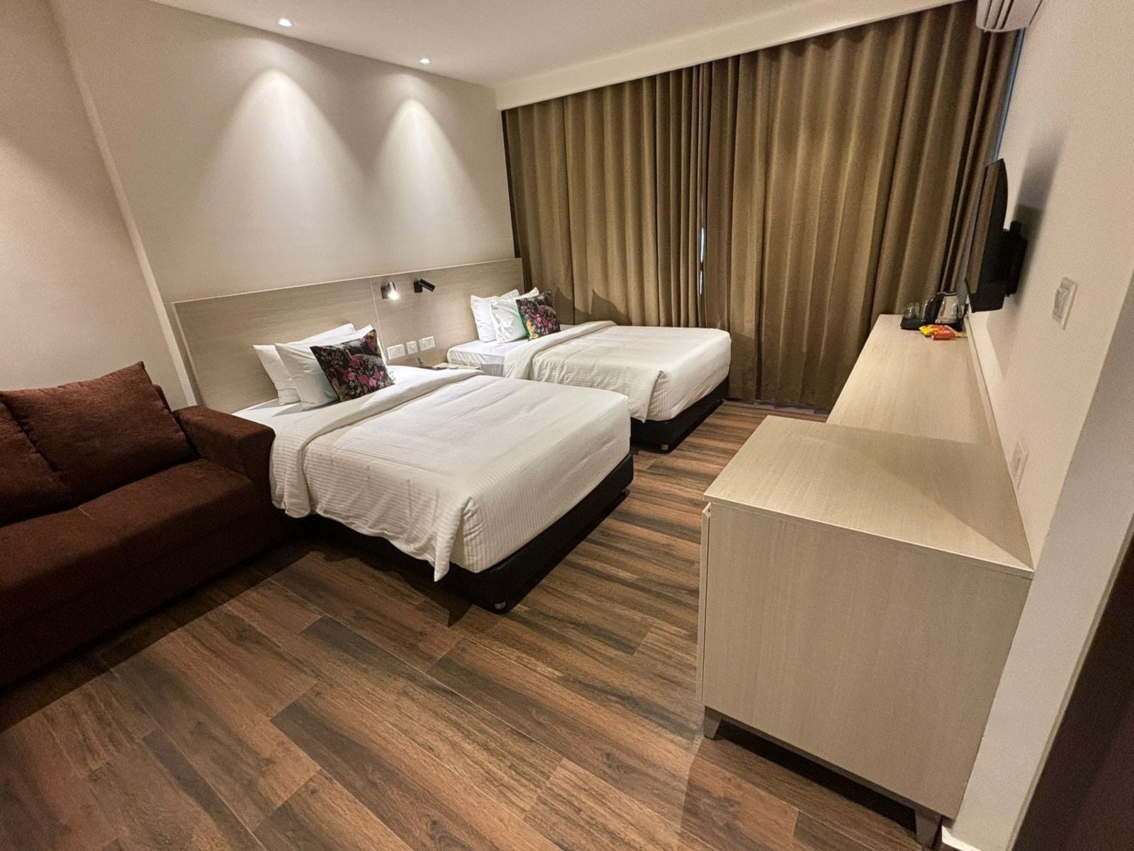 Una habitación de hotel con dos camas, un sofá, un escritorio y una televisión.
