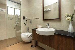 A modern bathroom with a toilet, sink, and shower. - Presidency Airport Hotel (Aluva)