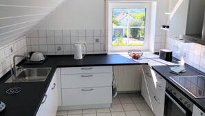 Ett modernt kök med vita skåp, svarta bänkskivor, ett fönster med utsikt över grönområden och en inbyggd ugn.