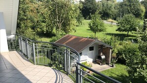 En balkong med utsikt över ett hus med en grillplats och en trädgård.