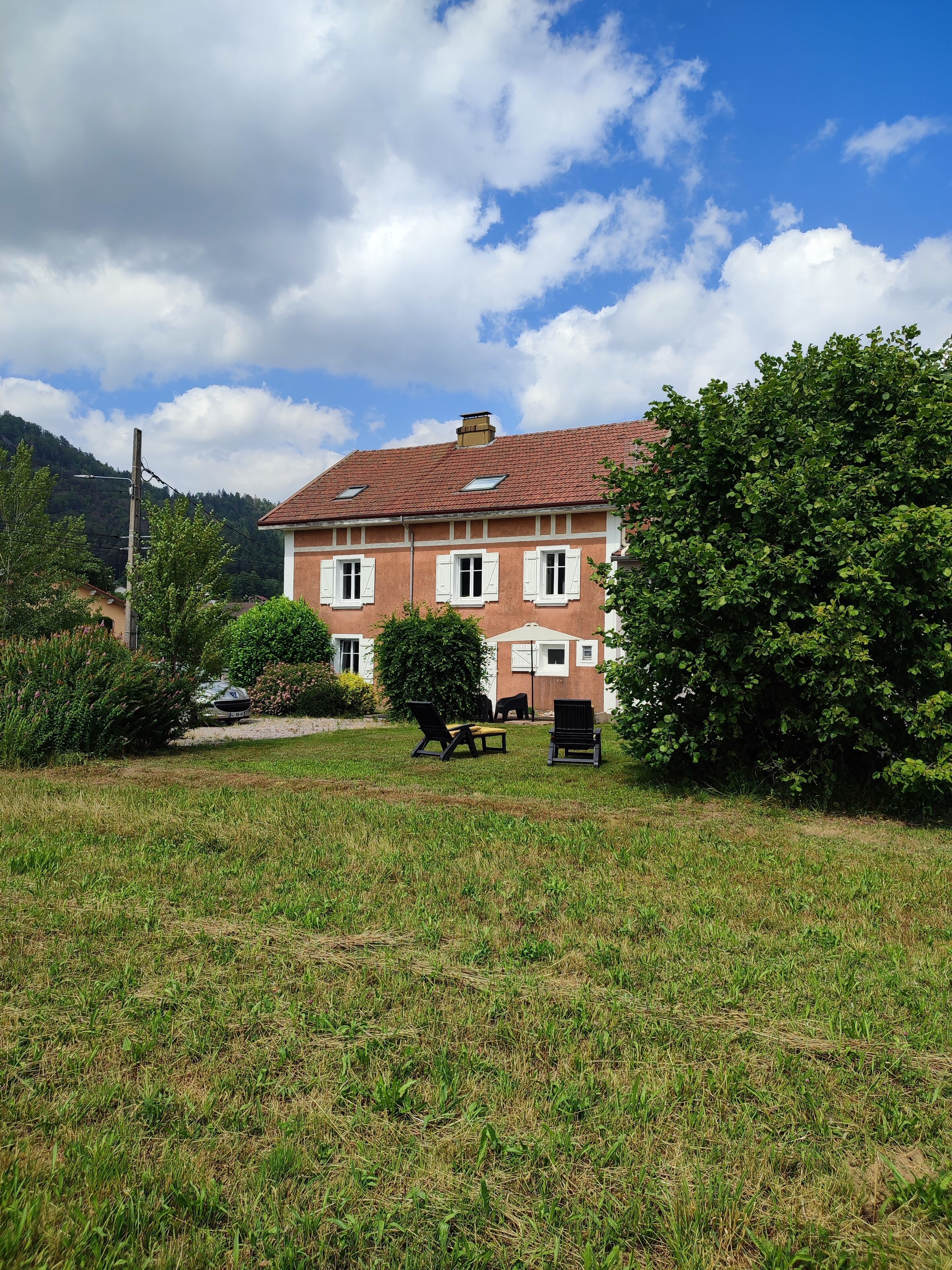 A two-story building with a red-tiled roof, surrounded by a grassy lawn and trees.