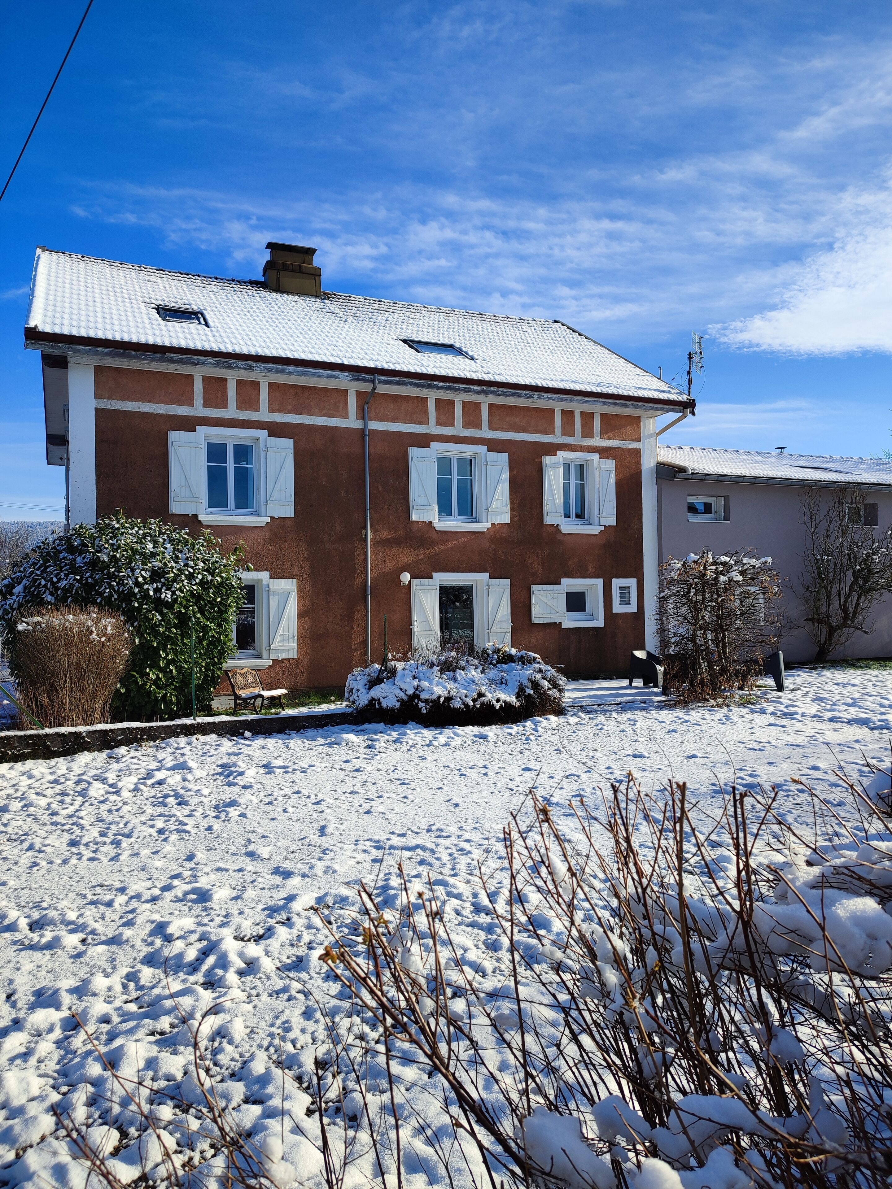 A two-story house with a snow-covered lawn and a clear blue sky.