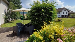 A patio with outdoor furniture, a large umbrella, and a garden with various plants.