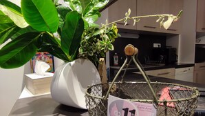A kitchen area with a potted plant on the counter, a coffee machine, and a basket with a price tag.