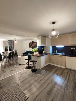 Een moderne keuken met een centraal eiland, houten vloeren en een eethoek met een kerstboom.