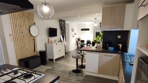 A modern kitchen with a gas stove, wooden flooring, and a dining area with a table and chairs.