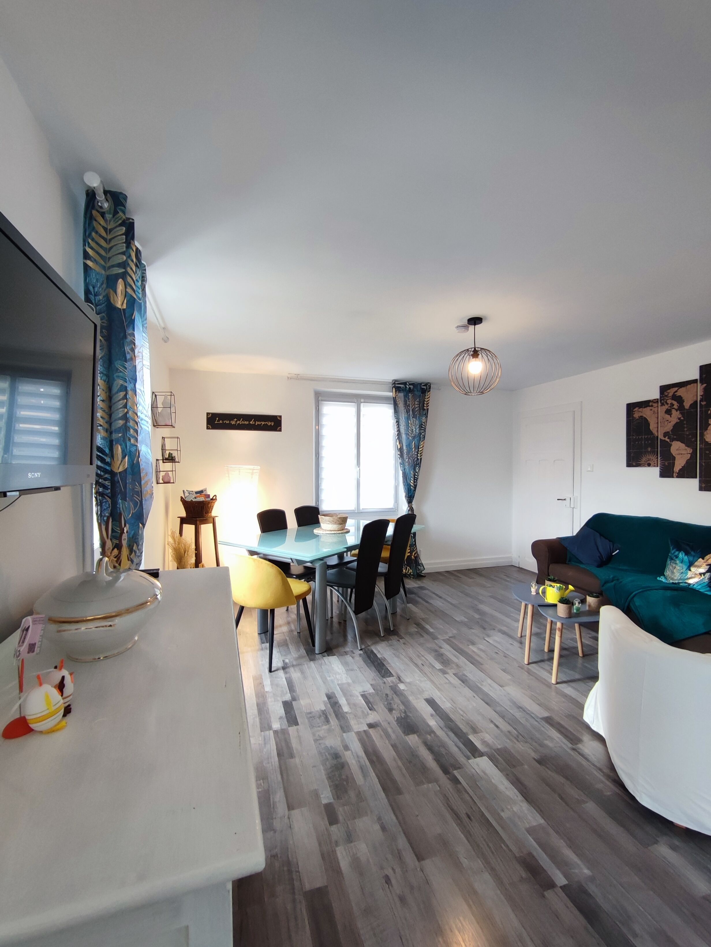 A modern living room with a dining area, featuring a sofa, a coffee table, and a dining table with chairs.