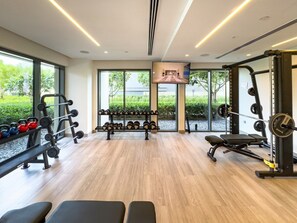Une salle de sport équipée de matériel de musculation, de bancs et d’un écran de télévision.