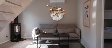 A modern living room with a sofa, coffee table, and a unique circular mirror with lights.