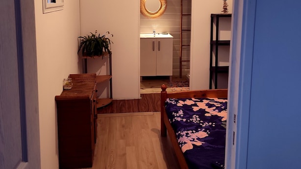 A narrow room with a bed, a small desk, a mirror, and a window. - Chambre Privée Chez Jo, en Bordure de Savane (Saint Paul)
