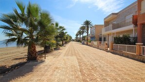 Eine Küstenstraße, gesäumt von Palmen und Gebäuden mit Balkonen.