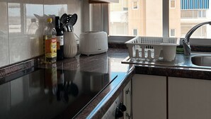 Eine moderne Küche mit Dunstabzugshaube aus Edelstahl, eingebautem Toaster und einem Fenster mit Blick auf Wohnhäuser.