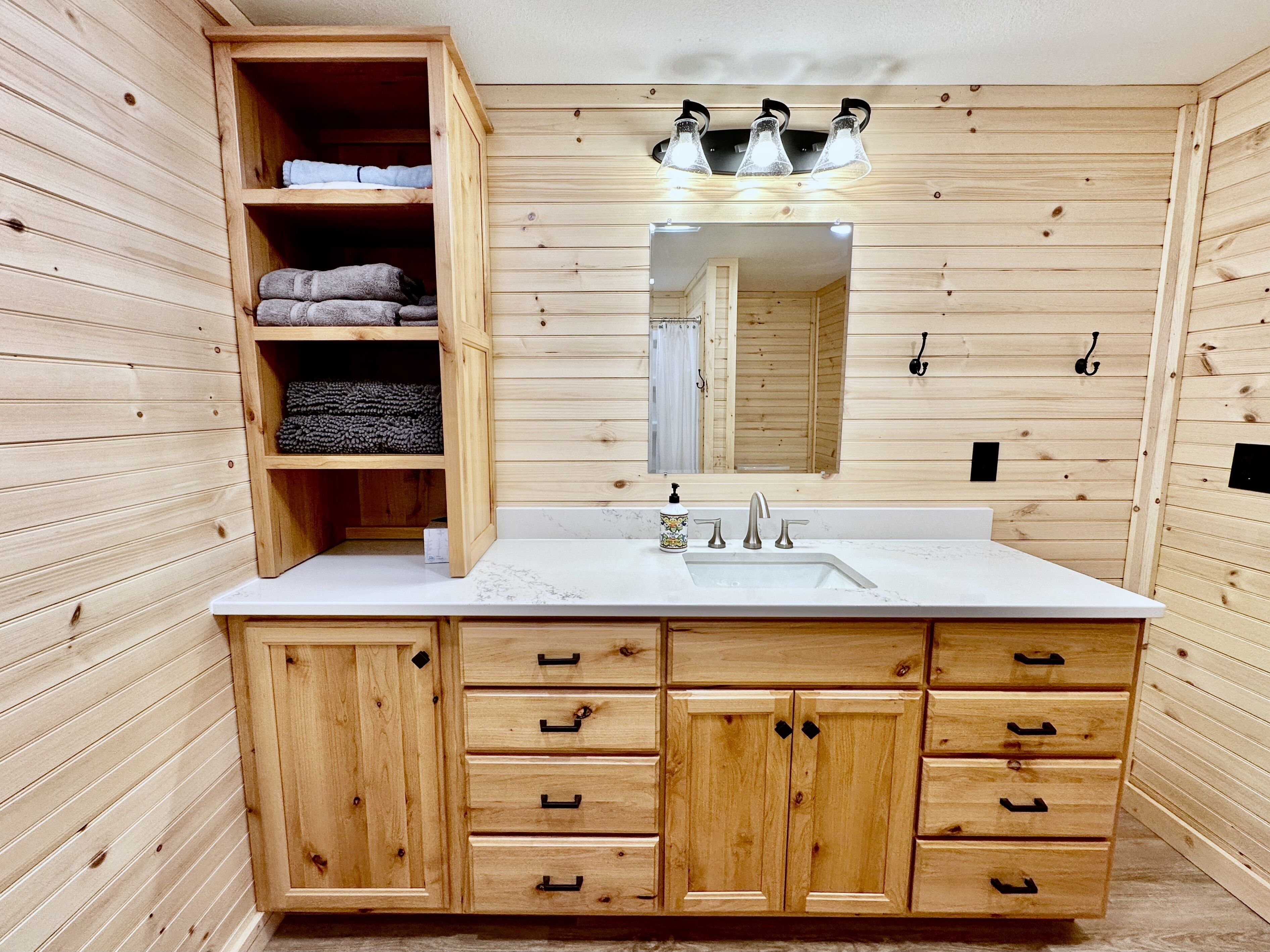 A wooden cabin-style bathroom with a sink, mirror, and wooden cabinets.