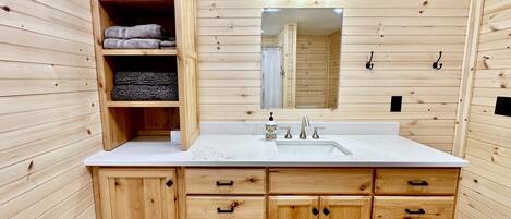 A wooden cabin-style bathroom with a sink, mirror, and wooden cabinets.