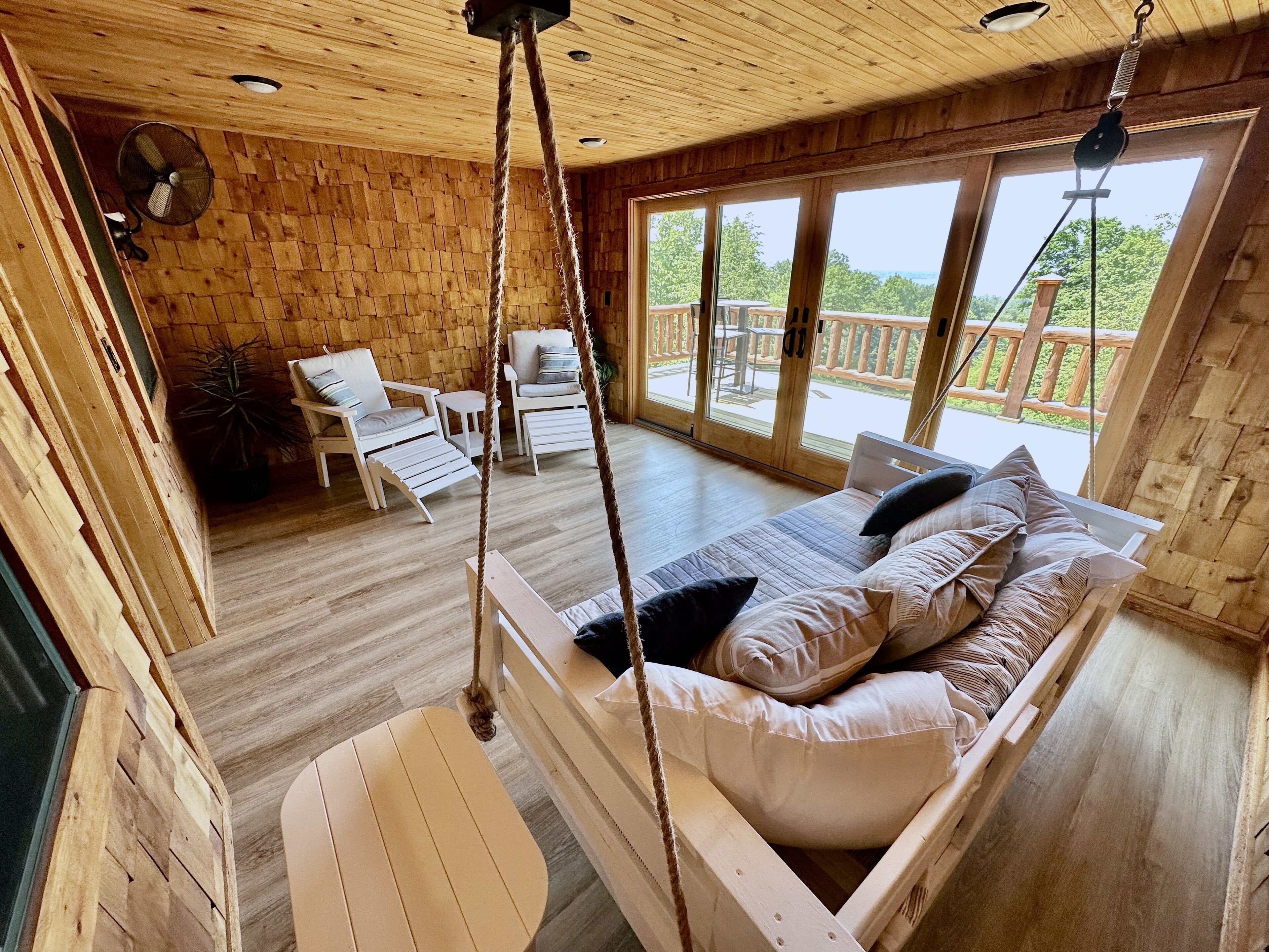 Eine Holzhütte mit Bett, Stühlen und einem Balkon mit Blick.