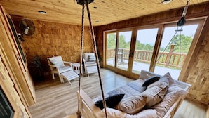 A wooden cabin with a bed, chairs, and a balcony with a view.